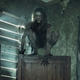 A pale, long-haired, feral man crouches atop on a chair on The Walking Dead.